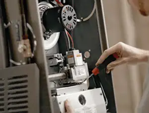 Furnace repair technician inspecting internal components and wiring in Louisville, KY