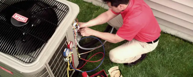 HVAC technician servicing an outdoor air conditioner unit in Louisville, KY