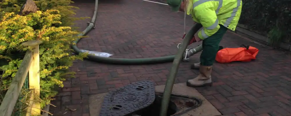 Septic tank cleaning technician servicing a septic tank with a vacuum hose in Louisville, KY